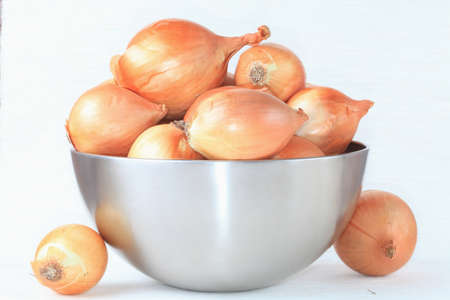 Onion in the iron bowl closeup on a light background  の写真素材
