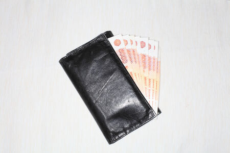 Black wallet and money of five-thousandth of Russia close-up on a light background.