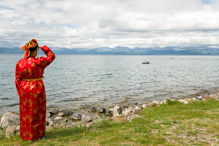 Woman in national dress looking at the lake Hovsgol, Mongoliaの写真素材