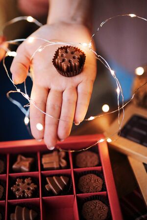 Women's hands hold a beautiful Christmas box with natural milk chocolates handmade in the form of...