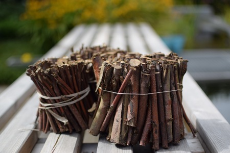 Small twigs bundled together on a bench in a traditional garden.の写真素材