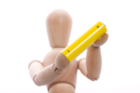 wooden mannequin doll model. Keep in hands a yellow battery or accumulatorの写真素材