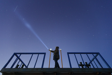 Silhouette of a man with a flashlight, observing beautiful. Astronomy, orientation, clear sky concept and background. UFO and searching, waiting miracle, torchの写真素材