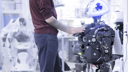 Engineer adjusts the robot. Engineer sets up a new robot. Clicks on the screen of the robot. Works...