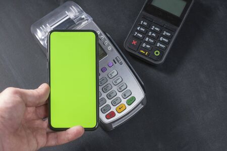 Top view of person using contactless payment with smartphone. Clear green mockup screen template of...