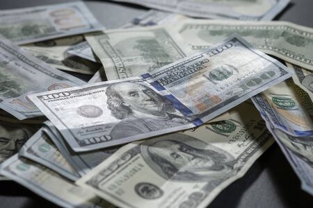 One hundred dollars pile as background. Many American dollars are slowly falling onto the table. Man...