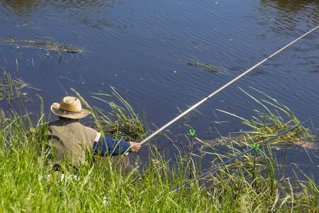 The river Kargat, Novosibirsk oblast, Siberia, Russia - June 12, 2016: a fisherman catches a fish on...