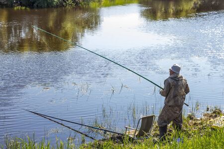 The river Kargat, Novosibirsk oblast, Siberia, Russia - June 12, 2016: a fisherman catches a fish on the river on a floatのeditorial素材