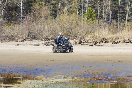 Russia, Siberia, Novosibirsk region, Ob river - April 24, 2016: the family of three rides a Quad bikeのeditorial素材