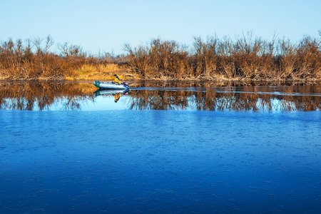 Chaus river, Kolyvan district, Novosibirsk region, Western Siberia, Russia-October 27, 2018: fisherman floating on an inflatable boat with a motor on the autumn riverのeditorial素材