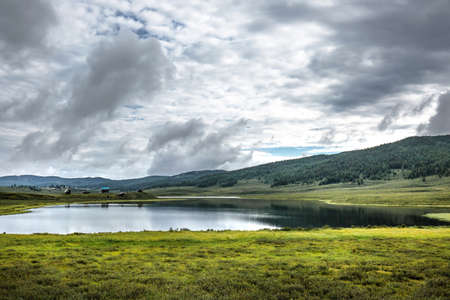 A small mountain lake surrounded by mountains and coniferous taiga. Ulagan district of the Altai Republicの写真素材