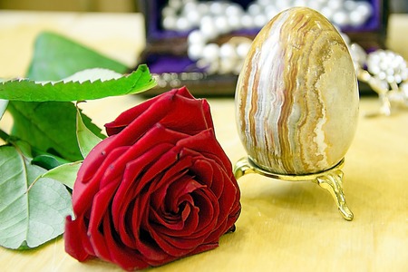 An easter egg, rings, pearl necklace in a jewelry box and a red rose.の写真素材