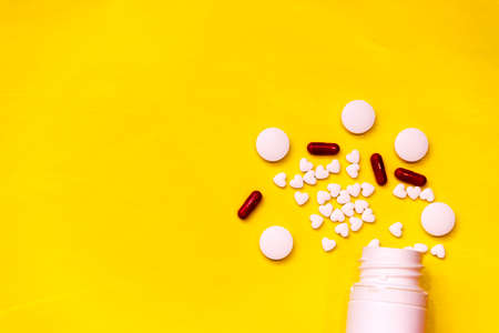 white tablets on yellow background. top view