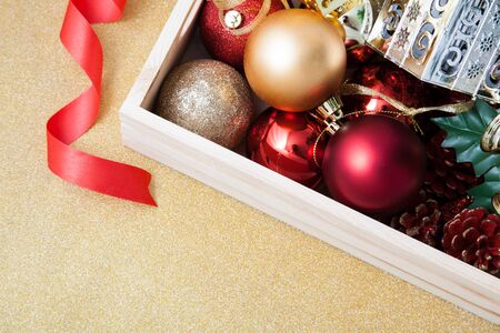 Box filled with Christmas decorations on golden backgroundの写真素材