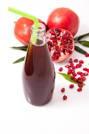 Isolated pomegranate juice with pomegranate, leaf, and seed on white backgroundの写真素材