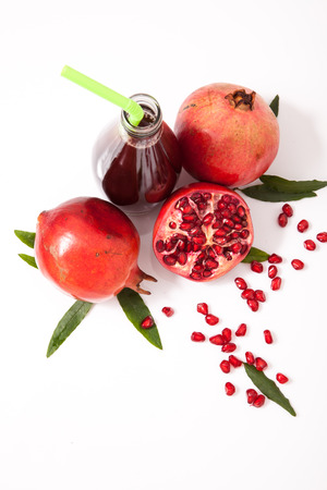Isolated pomegranate juice with pomegranate, leaf, and seed on white backgroundの写真素材