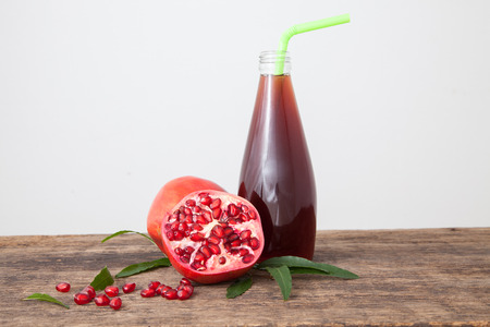 Isolated pomegranate juice with pomegranate, leaf, and seed on white backgroundの写真素材