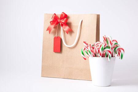 Isolated brown paper shopping bag and blank tag, label with candy cane on white backgroundの写真素材
