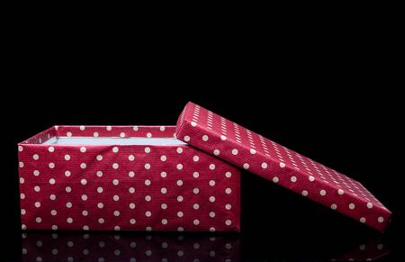 Isolated polka dot red box with bow on black background