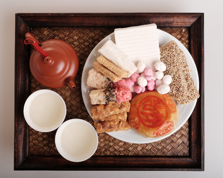 Hot Chinese tea in pot and cup with variety of traditional Chinese dessertson bamboo trayの写真素材