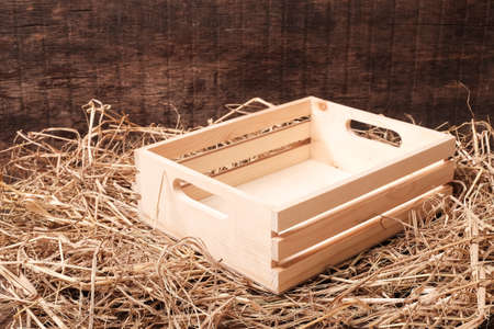empty wooden box on straw isolated on wooden backgroundの写真素材