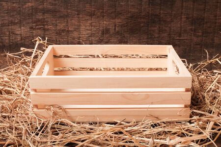 empty wooden box on straw isolated on wooden backgroundの写真素材