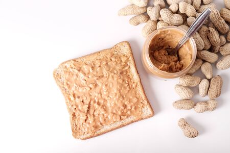 chunky peanut butter on whole wheat bread and peanut butter in jar isolated on white background