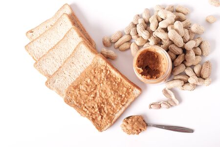 chunky peanut butter on whole wheat bread and peanut butter in jar isolated on white background