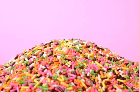 pile of colorful sugar sprinkles on pink background, decoration for ice cream and bakeryの写真素材
