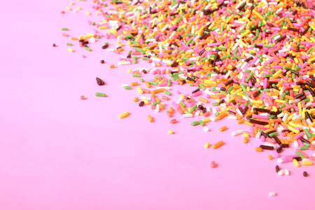 pile of colorful sugar sprinkles on pink background, decoration for ice cream and bakeryの写真素材