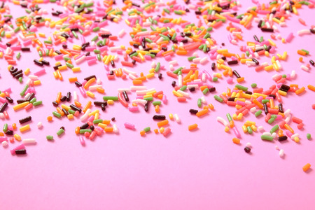 colorful sugar sprinkles scattered on pink background, decoration for ice cream and bakeryの写真素材