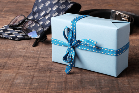 Father's day composition. Gift box, tie, glasses and belt with space for text on wooden table topの写真素材
