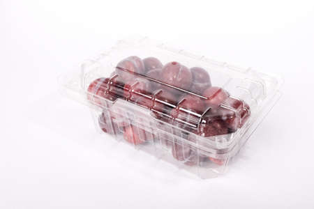 Fresh red plums in plastic container isolated on white backgroundの写真素材