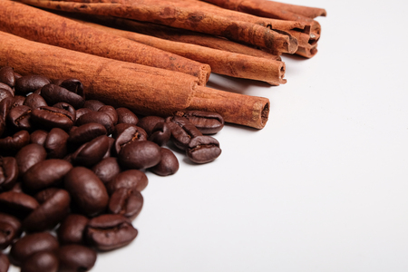 Coffee beans and cinnamon sticks with space for text on white background.の写真素材