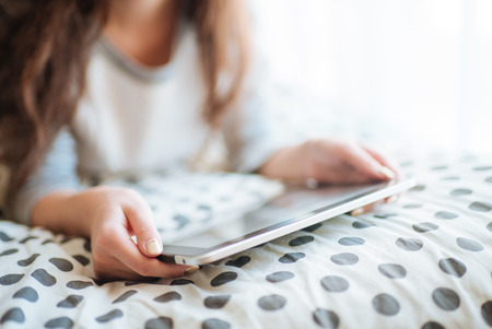 Woman lying in bed with digital tablet touching with finger