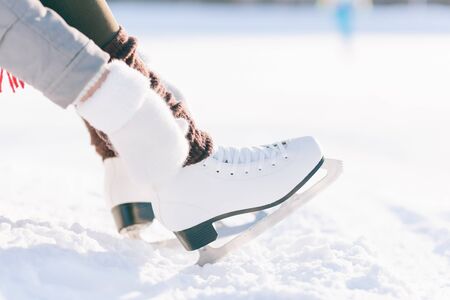 Girl in dress skates mittens tying shoelaces and prepare for skatingの写真素材