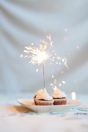 Birthday Cupcake with a sparkler over a blue background.の写真素材