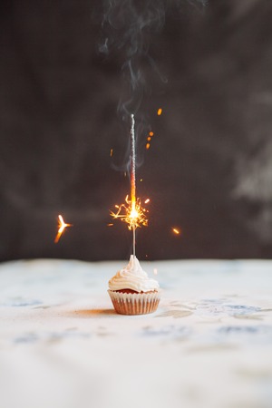 Birthday Cupcake with a sparkler over a blue background.の写真素材