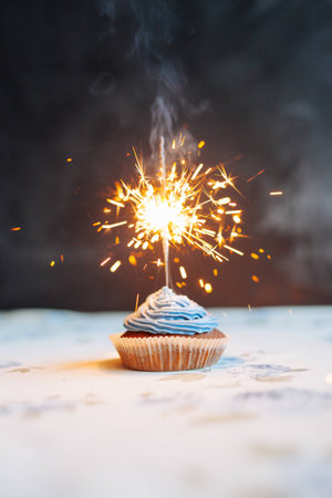 Birthday Cupcake with a sparkler over a blue background.の写真素材