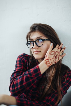 Funny stylish sexy smiling beautiful young hippie woman model in summer white fresh hipster clothes sitting in the streetの写真素材