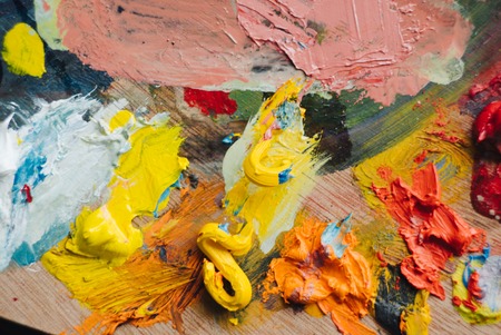 Painter mixes yellow and red oil paint on the palette. Closeup of paint mixing process in art workplace.の写真素材