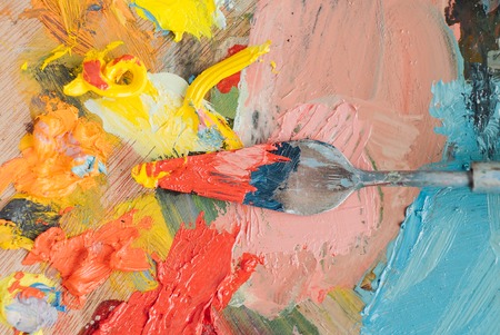 Professional acrylics orange paint on canvas and loaded palette knife.