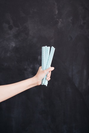 Woman hand hold cocktail straw blue on black background.の写真素材
