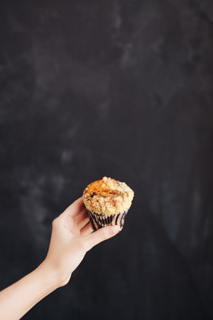 Woman holding a chocolate muffin on black background.の写真素材