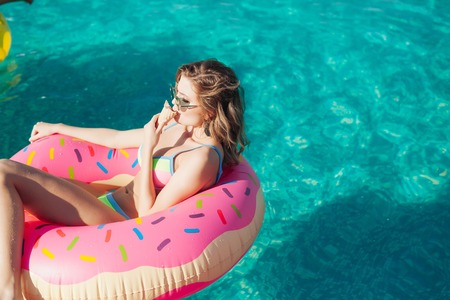 sexy woman girl in sunglasses eating ice cream at the pool. 20sの写真素材