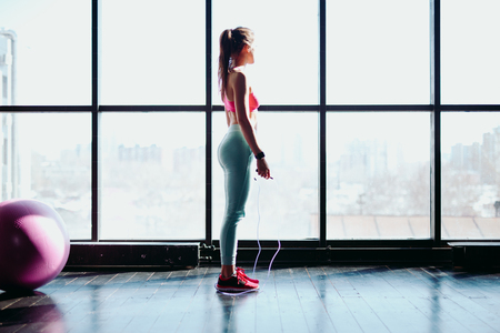 Fitness concept. Healthy lifestyle. Young slim woman jumping with skipping rope in gymの写真素材