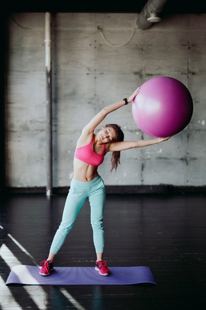 fitness, sport, training and people concept - smiling woman flexing abdominal muscles with exercise ball in gymの写真素材