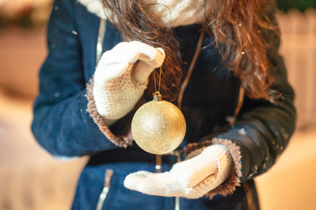 Female hands holding a Christmas gold ball. Frosty winter day in snowy forest. Merry Christmas and Happy New Year themeの写真素材