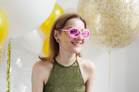Portrait of happy funny young woman in pink heart shaped glasses.