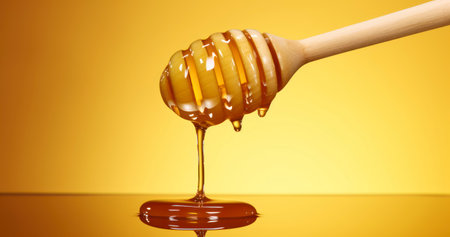 The Allure of Honey Dripping from a Wooden Dipper on a Bright Yellow Backgroundの素材